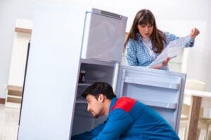 Technicien réparant un réfrigérateur qui ne refroidit plus alors que le moteur fonctionne