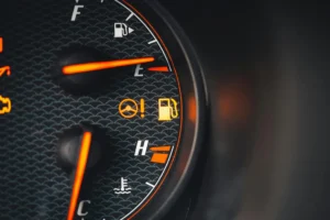 Vue rapprochée d'un voyant orange allumé sur un tableau de bord de voiture, signalant une alerte importante