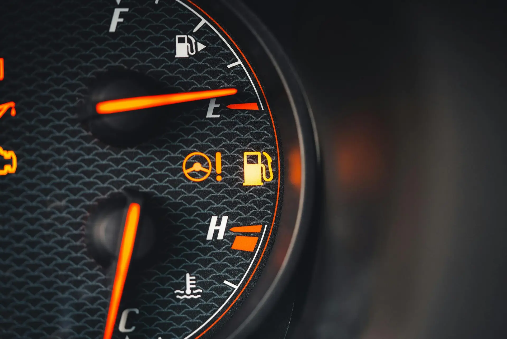 Vue rapprochée d'un voyant orange allumé sur un tableau de bord de voiture, signalant une alerte importante