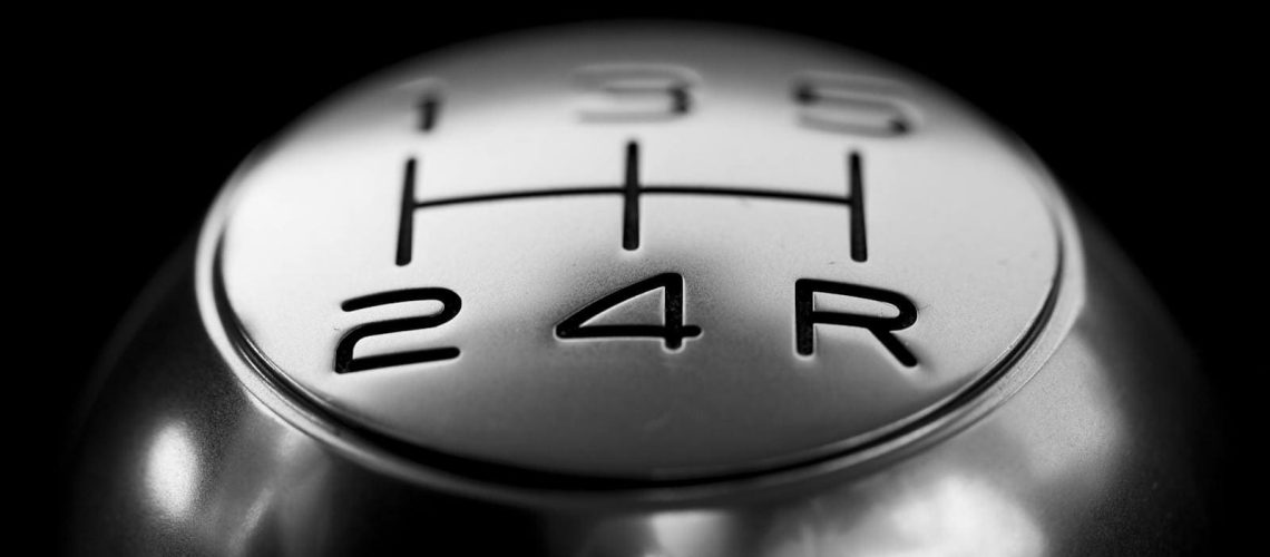 Detailed close-up of a stainless steel gear shift knob against a black background.