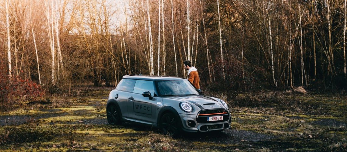 a man standing next to a car in a forest